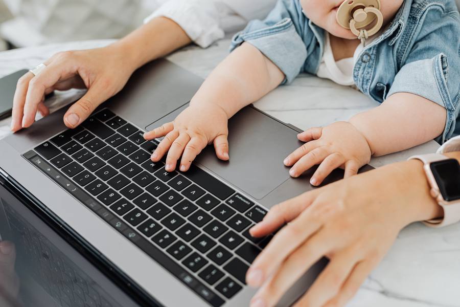 Mãos de mulher e de bebê sobre o laptop